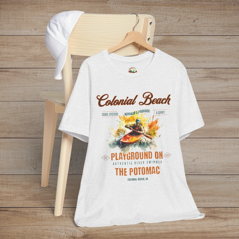 Colonial Beach Premium T-Shirt Playground on the Potomac design displayed on an ash gray t-shirt, laid flat on a wooden chair with a white cap for a relaxed beach vibe