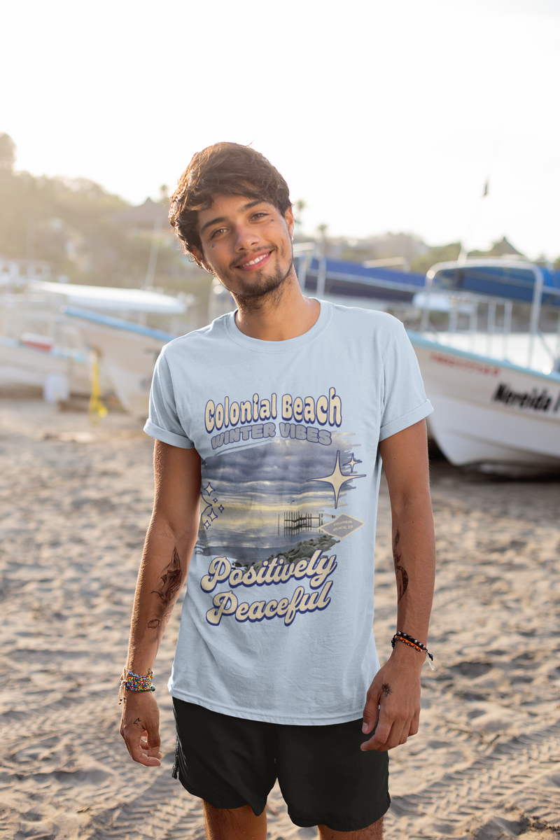 man wearing colonial beach winter vibes baby blue premium t-shirt standing on the beach