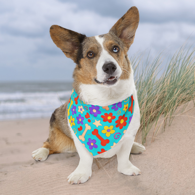 Extra-large dog wearing vibrant flower-and-bone bandana on beach with grassy dunes