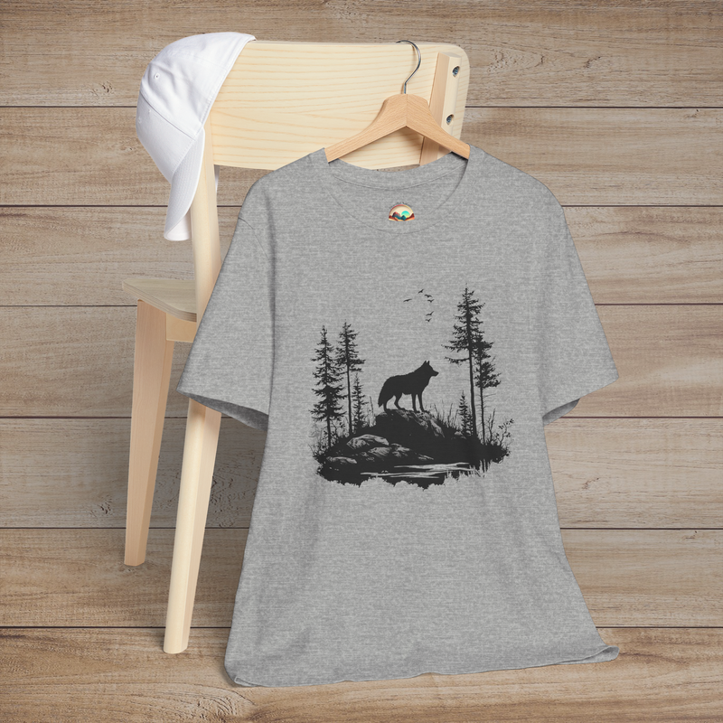Heather grey t-shirt featuring a lone wolf howling on a rocky cliff surrounded by evergreen trees and flying birds, symbolizing strength and independence
