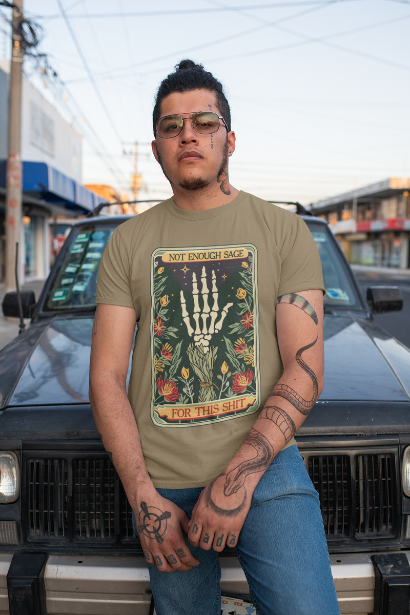 Tattooed male model posing outdoors in Heather Olive Not Enough Sage for This Sh*t T-Shirt, bold skeleton hand sage graphic with goth-boho appeal