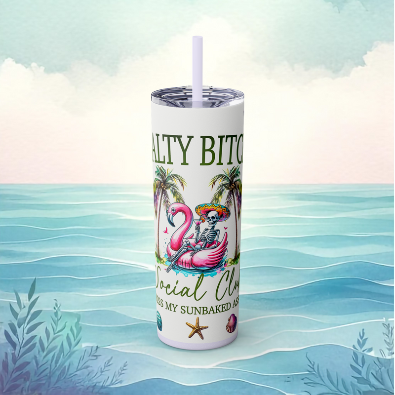 Front view of the Salty Bitch Social Club skinny tumbler in glitter lilac, featuring a lounging skeleton in a pink flamingo float, palm trees, and beachy vibes