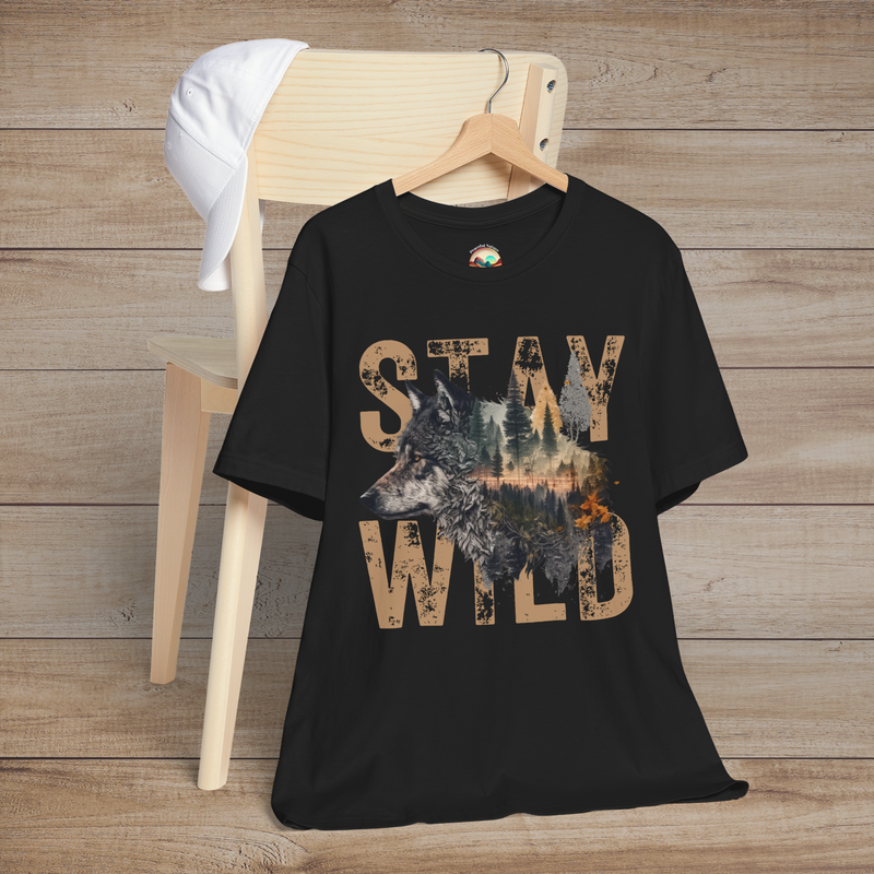 Classic black "Stay Wild" T-shirt with distressed tan letters and a dramatic wolf-and-forest graphic centerpiece, folded over a wooden chair for a bold nature-lover aesthetic