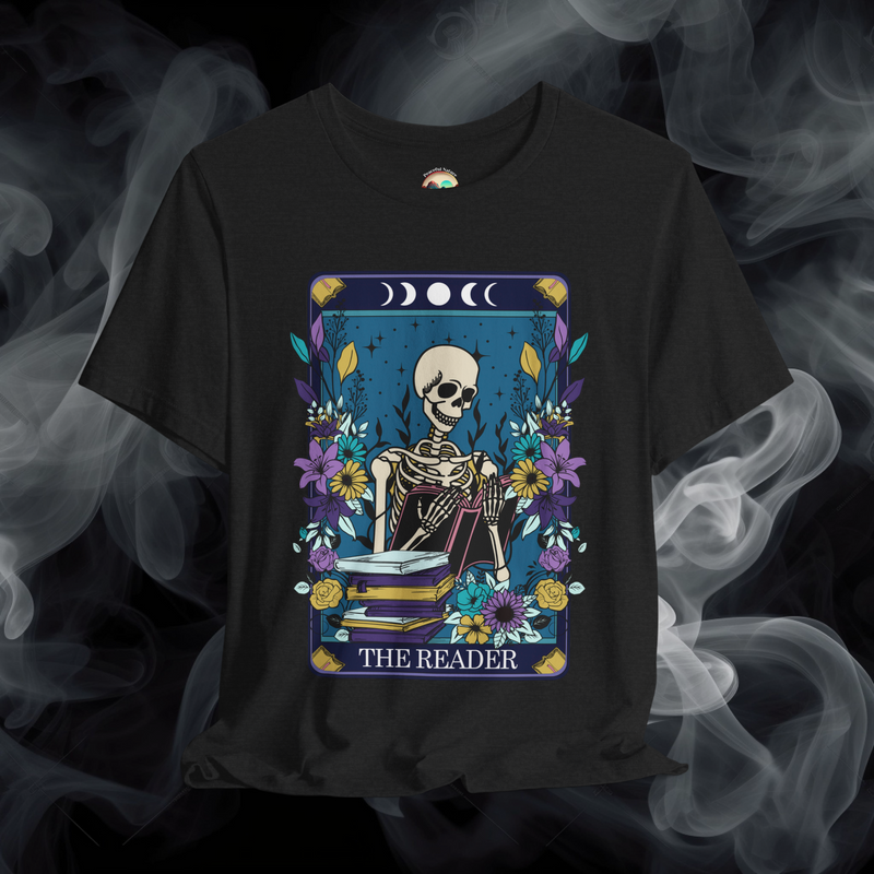 The Reader T-Shirt featuring a mystical skeleton reading a book surrounded by vibrant flowers and moon phases on black fabric