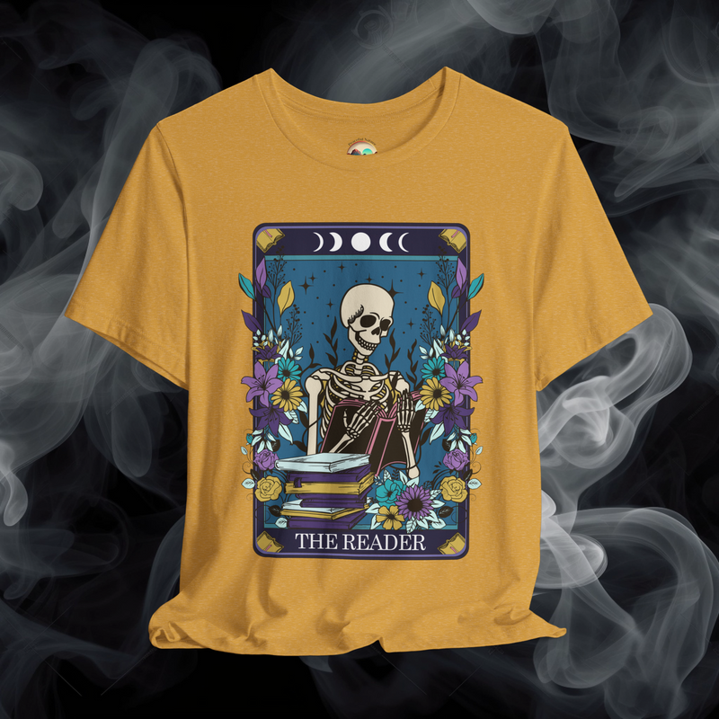 The Reader T-Shirt with a gothic Boho skeleton immersed in a book, framed by vibrant flowers and astrology symbols on heather mustard yellow fabric