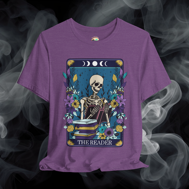 The Reader T-Shirt showcasing a gothic skeleton reading amid flowers and lunar symbols, printed on heather purple fabric