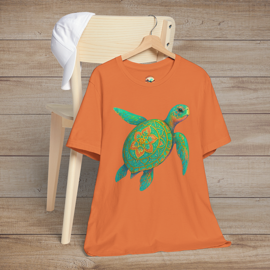 Burnt orange t-shirt with vibrant mandala sea turtle graphic, displayed on wooden chair