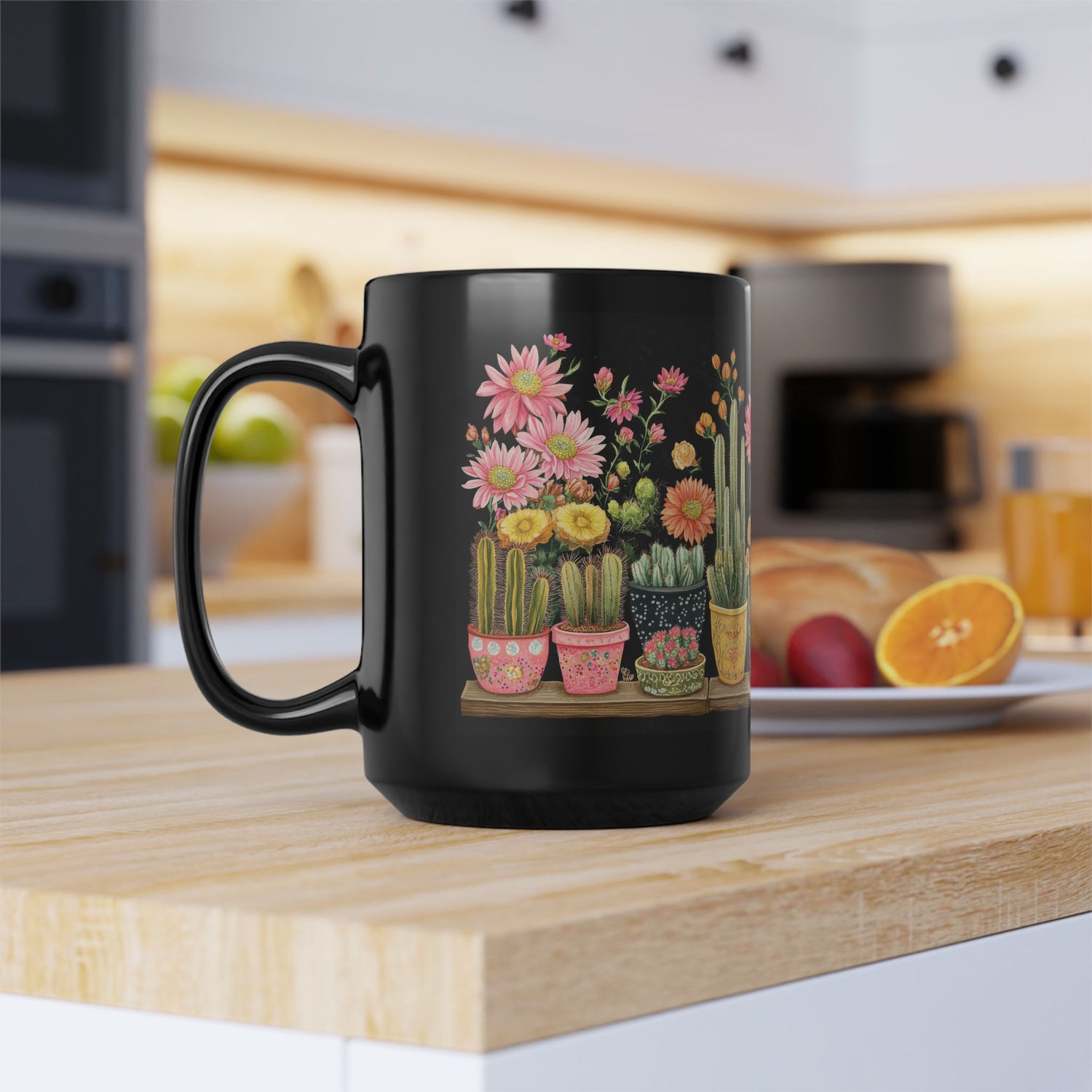 A 15 oz black ceramic mug on a wooden kitchen counter, showcasing colorful cacti in pink, yellow, and green pots on the left side of the wrap-around design