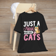 Black t-shirt featuring a cute cartoon orange cat wearing a nurse cap, holding a needle, with the text Just a Nurse Who Loves Cats