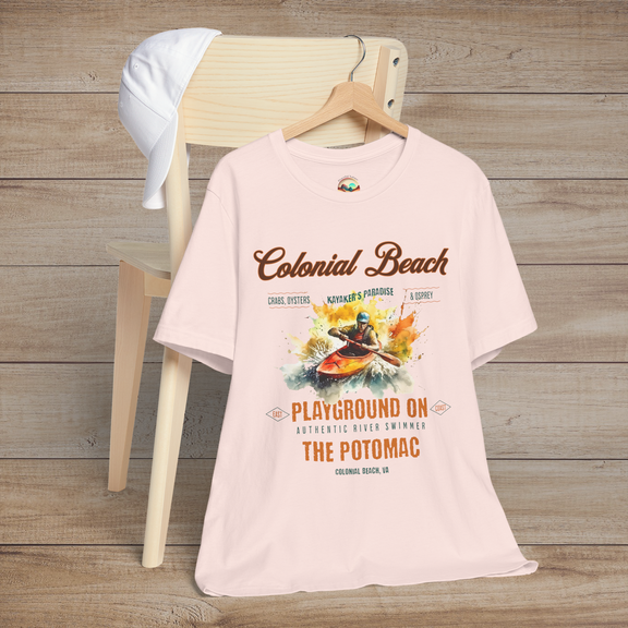 Colonial Beach Premium T-Shirt Playground on the Potomac design showcased on a soft pink t-shirt, placed on a wooden chair next to a white cap, ideal for beach lovers
