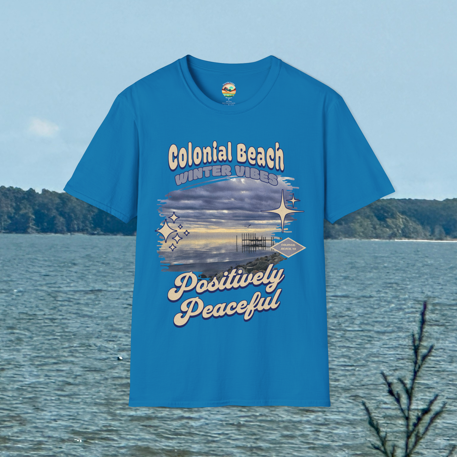 Colonial Beach Winter Vibes Soft Fit T-Shirt in Sapphire Blue, displayed hanging by scenic water view