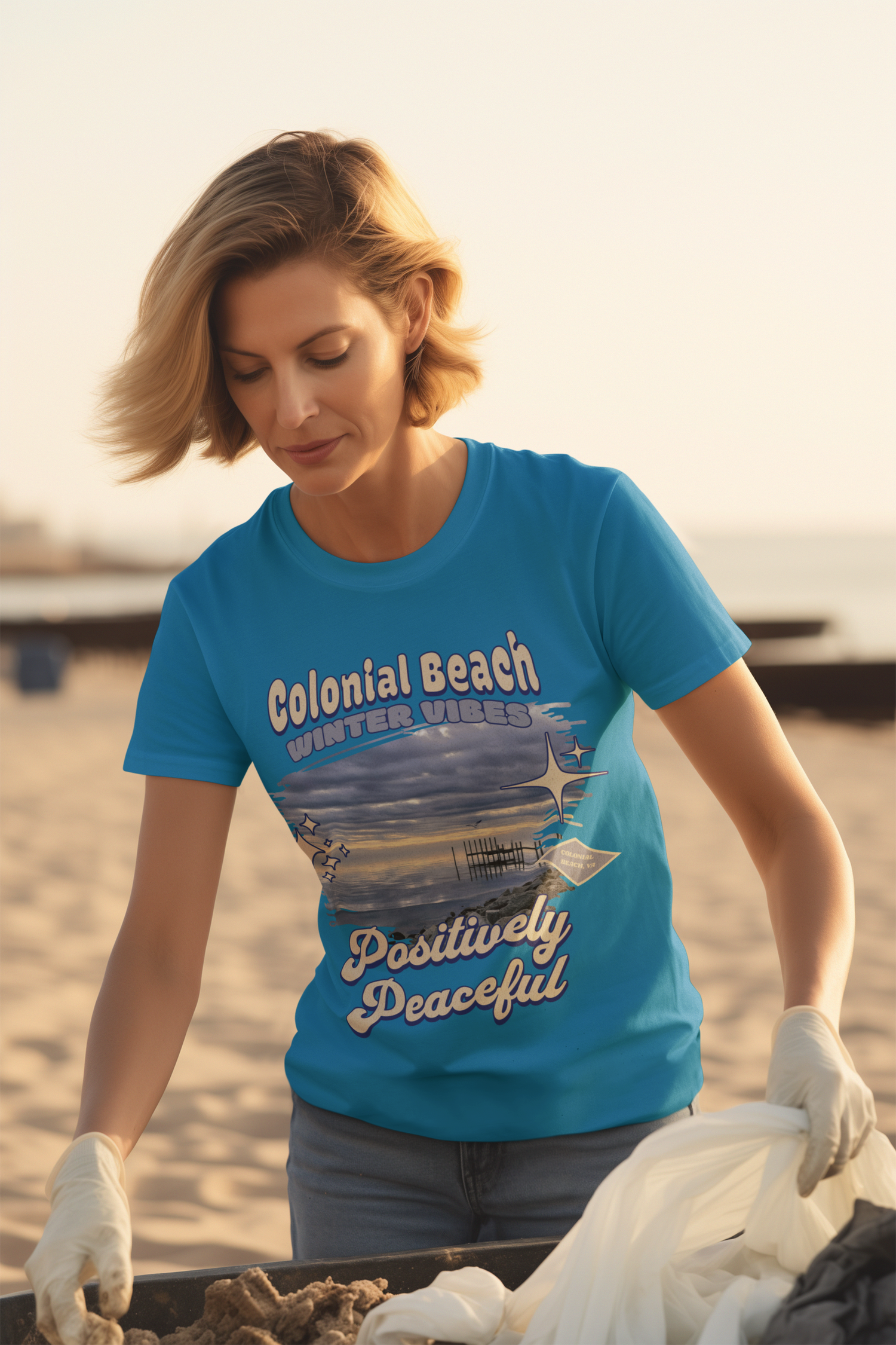 Woman wearing Sapphire Blue Colonial Beach Winter Vibes Soft Fit T-Shirt while participating in a beach cleanup