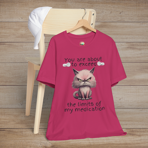 Sarcastic cranky cat t-shirt in berry pink, showing angry cartoon cat and humorous text about testing patience, laid flat on a wooden chair
