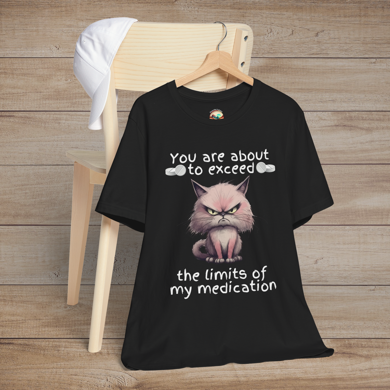 Funny cranky cat t-shirt in black featuring angry cartoon cat and sarcastic quote about medication limits, flat lay style for cat lovers and humor fans