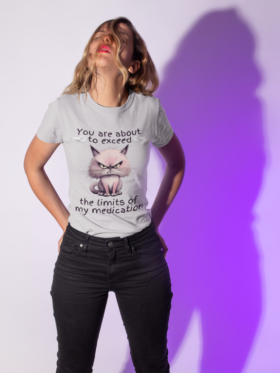 Playful woman wearing heather grey cranky cat t-shirt with angry cartoon cat and funny medication quote, posing under purple lighting, perfect sarcastic gift