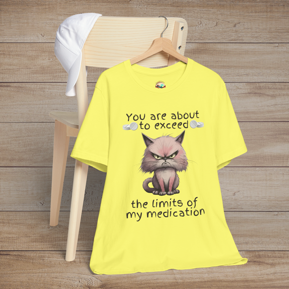 Bright yellow cranky cat t-shirt with angry cartoon cat and sarcastic medication quote, laid flat on chair, perfect humorous gift for cat lovers