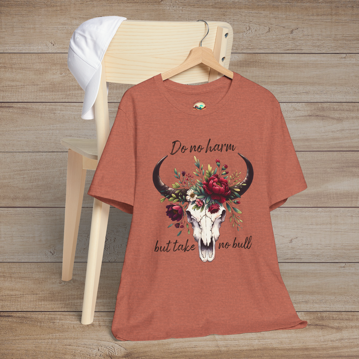 Flat lay of "Do No Harm But Take No Bull" t-shirt in heather clay with bull skull and floral crown
