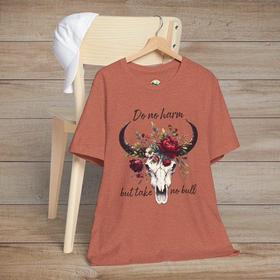 Flat lay of "Do No Harm But Take No Bull" t-shirt in heather clay with bull skull and floral crown