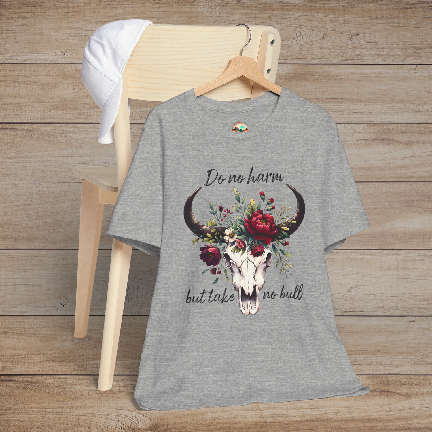 Flat lay of "Do No Harm But Take No Bull" t-shirt in heather grey with bull skull and floral crown
