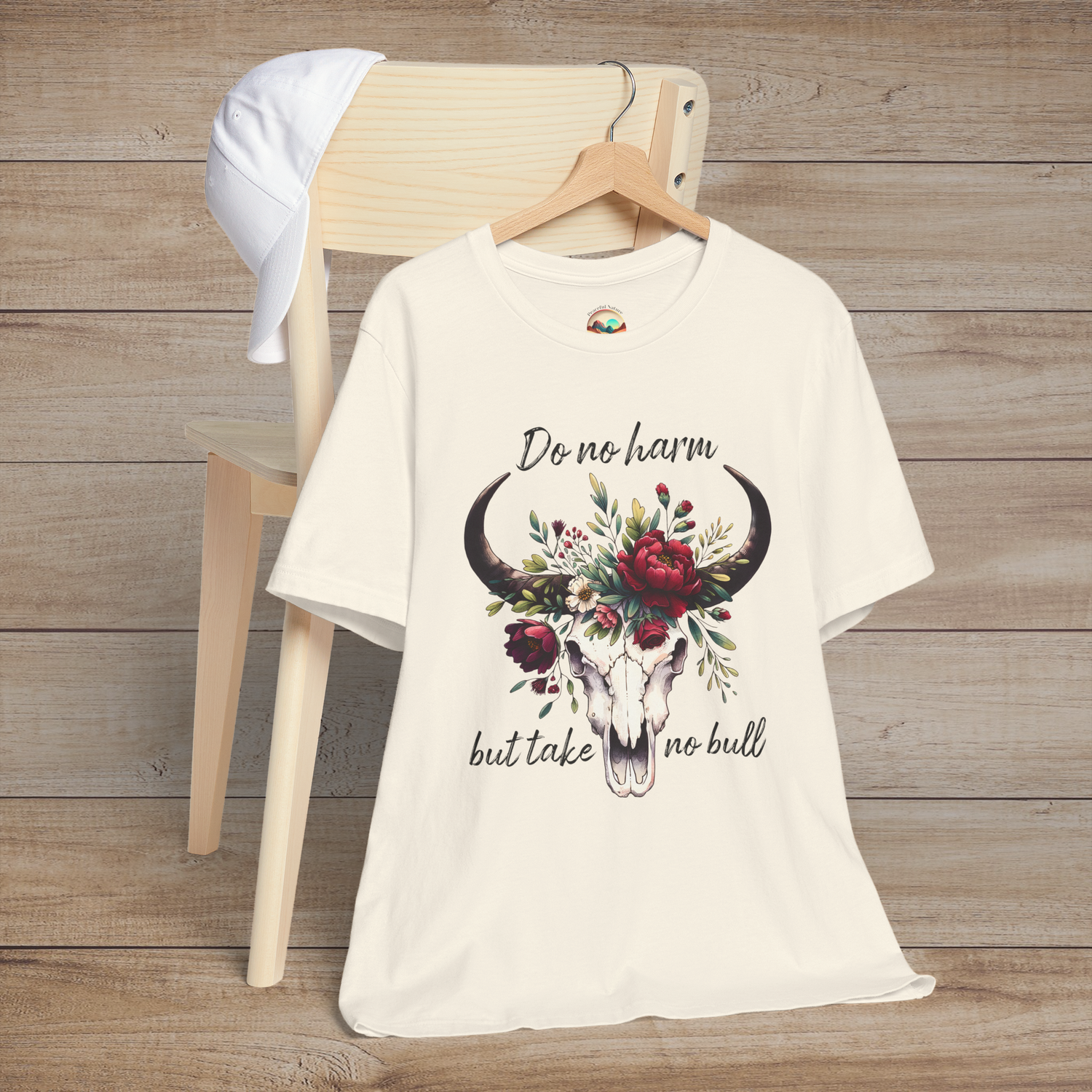 Flat lay of "Do No Harm But Take No Bull" t-shirt in natural with bull skull and floral crown