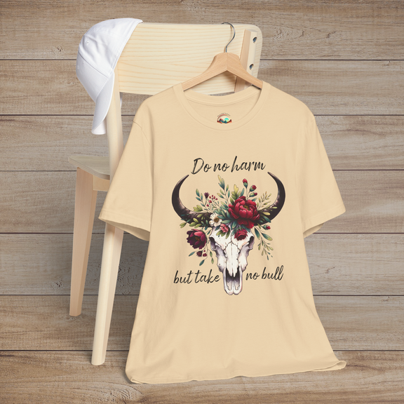 Flat lay of "Do No Harm But Take No Bull" t-shirt in soft cream with bull skull and floral crown