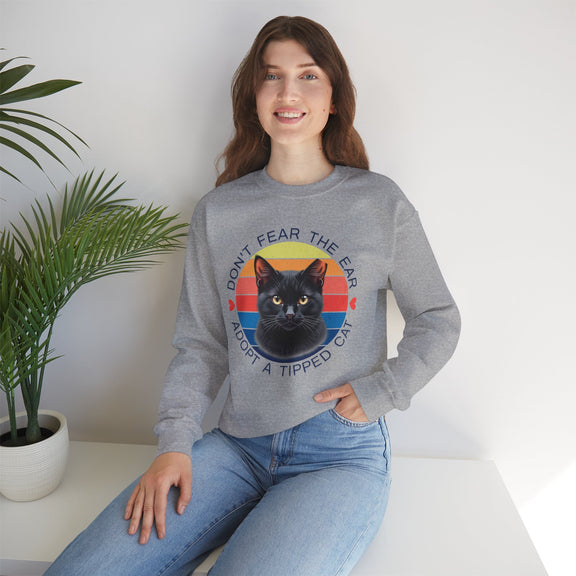 Athletic heather (heather grey) Gildan 18000 sweatshirt with ear-tipped black cat design and vintage sunset background, worn by woman indoors — cat adoption and community cat advocate sweatshirt.