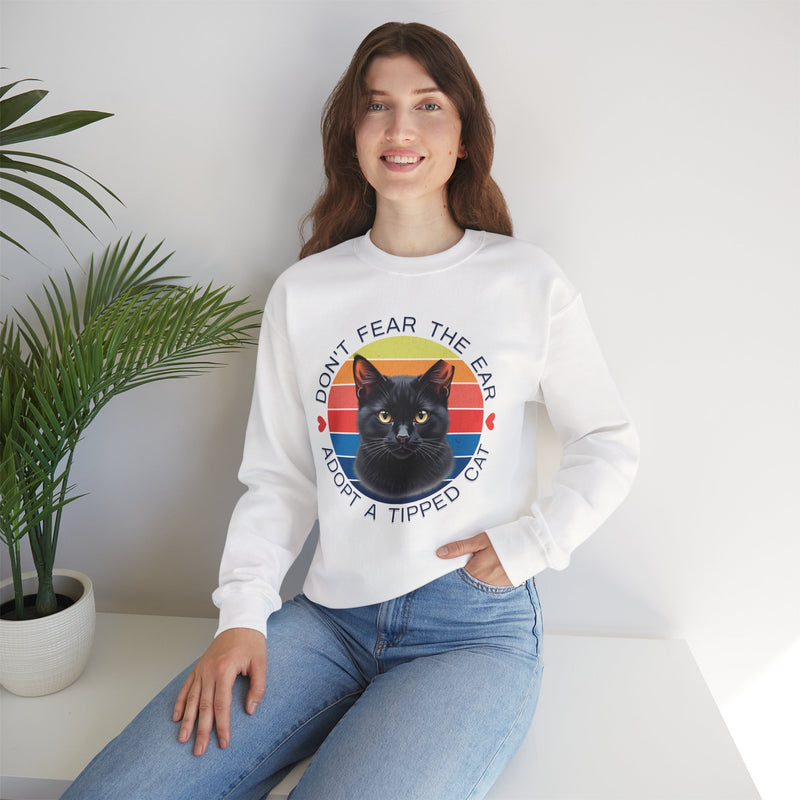 White Gildan 18000 sweatshirt with ear-tipped black cat design and vintage sunset background, worn by woman indoors — cat adoption and community cat advocate sweatshirt.