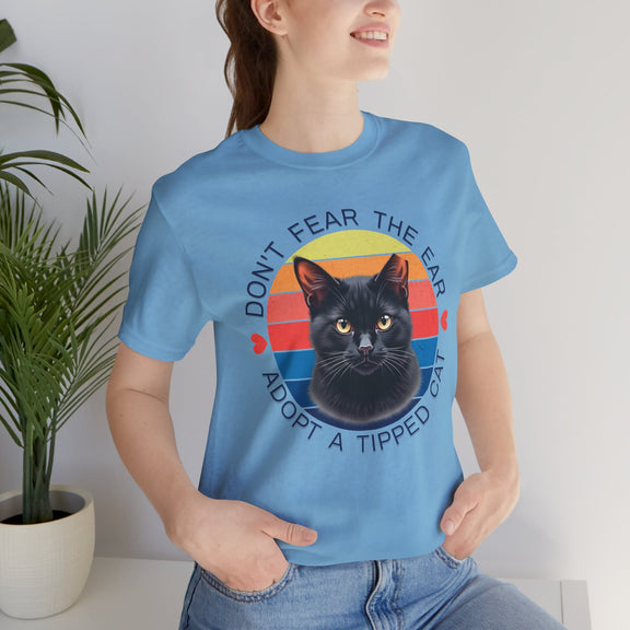 Ocean blue Bella Canvas 3001 t-shirt featuring ear-tipped black cat artwork and retro stripes, modeled by a smiling woman — community cat rescue and TNR support shirt