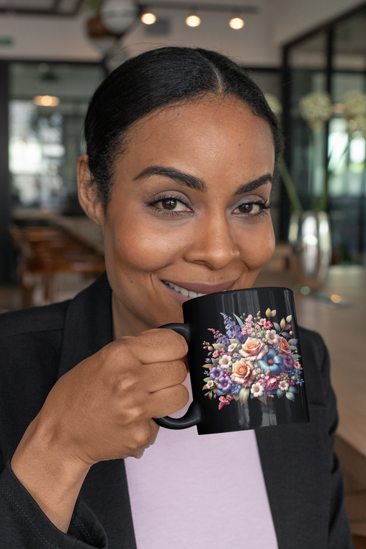 Woman smiling while holding an 11 oz black ceramic mug adorned with a vibrant floral bouquet design in various colors