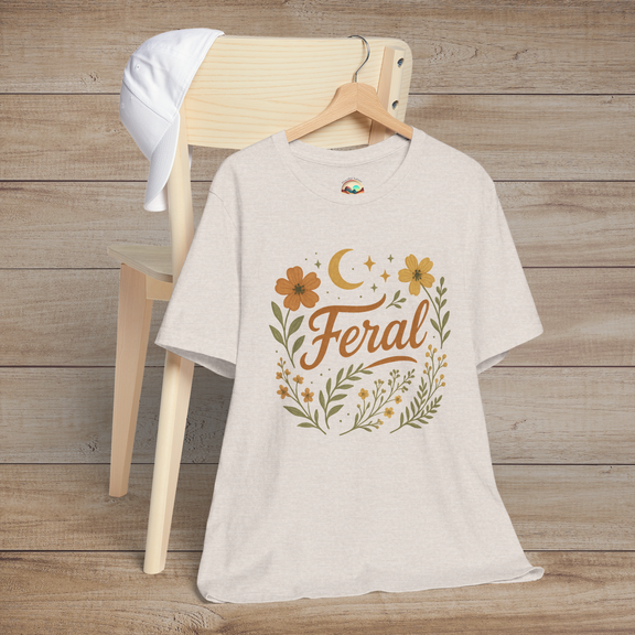 Feral t-shirt in Heather Dust with floral and moon design in elegant calligraphy, displayed on a chair with a cap