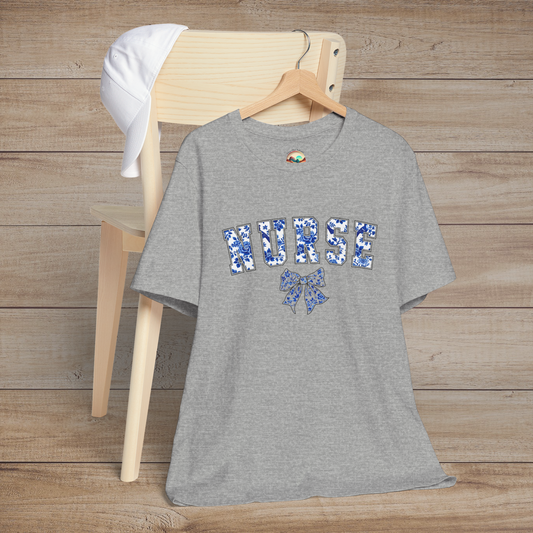 Heather grey t-shirt hanging on a wooden chair, featuring the word 'NURSE' in floral blue letters with a matching bow design – a stylish and elegant tribute to nurses