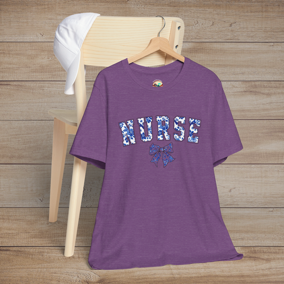 Heather purple nursing tee with floral 'NURSE' text and an elegant bow, hung stylishly on a chair – designed for proud and graceful nurses