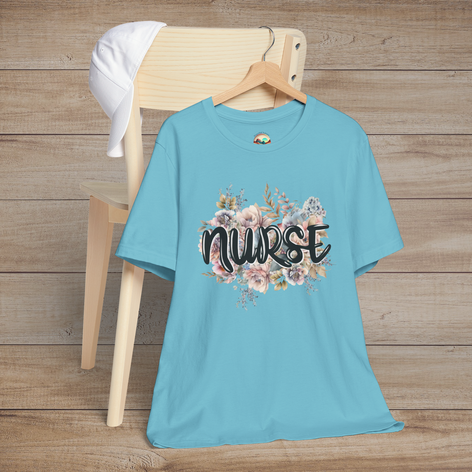 Turquoise Nurse Floral Premium Fit T-Shirt hanging on wooden hanger, featuring pastel floral design with graceful black text