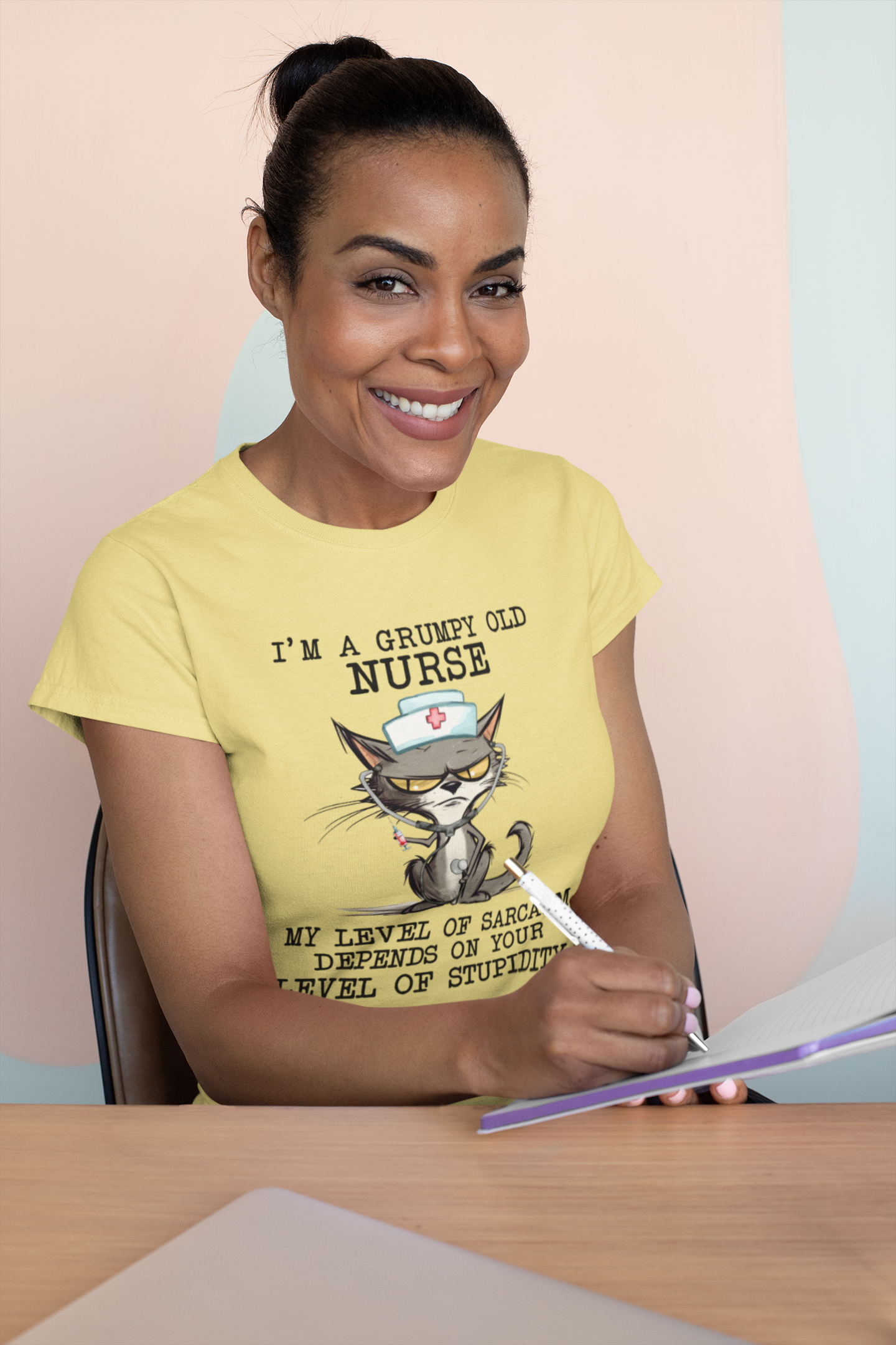 Happy woman writing in notebook while wearing Funny Nurse T-Shirt with grumpy cat illustration and sarcastic quote, premium maize yellow cotton fabric