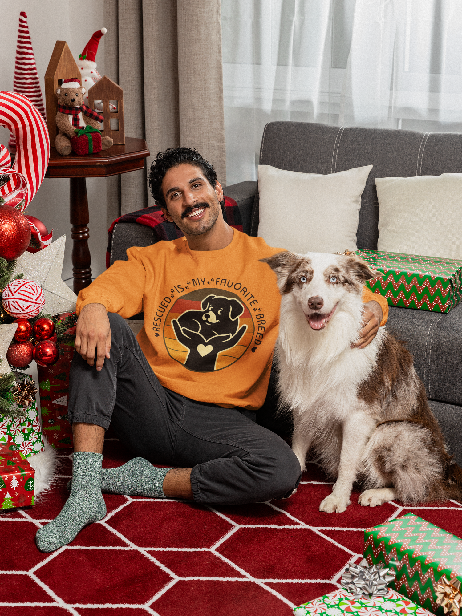 Model seated on floor with his dog, wearing Safety Orange Gildan 18000 Rescued Is My Favorite Breed sweatshirt.