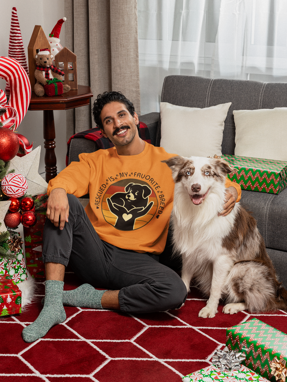 Model seated on floor with his dog, wearing Safety Orange Gildan 18000 Rescued Is My Favorite Breed sweatshirt.