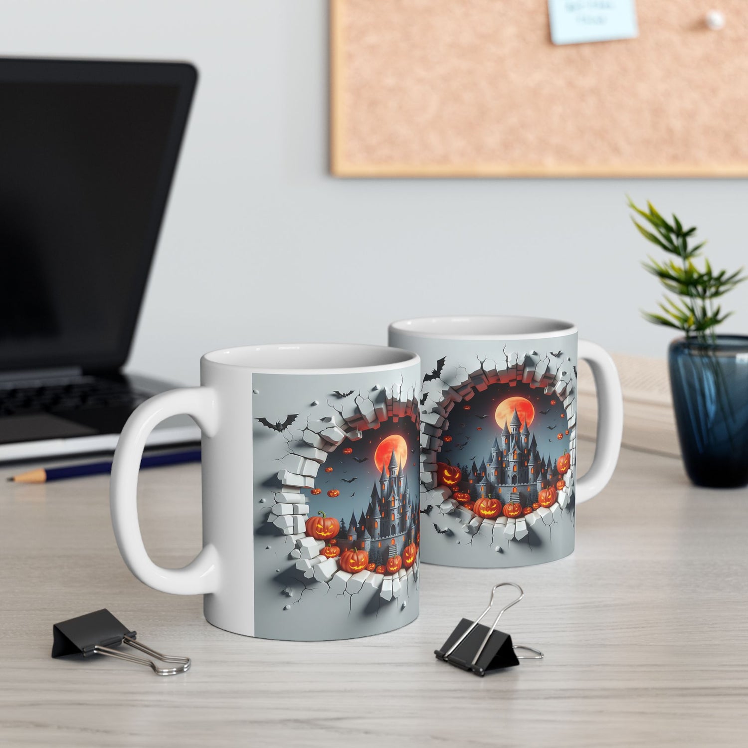 Left-side view of the 11 oz Halloween Mischief Mug, shown beside another mug 
 (right-view) on a modern desk. Features a haunted castle, glowing pumpkins, bats, and a wall-breaking effect. A great gift for Halloween lovers and office decor