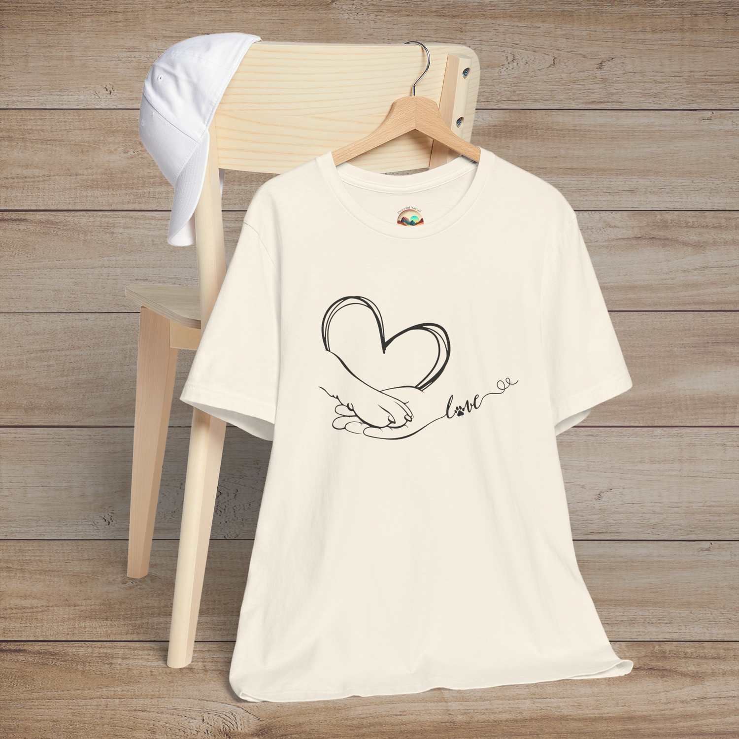 Natural color t-shirt with simple and elegant black line drawing of a hand, paw, heart, and flowing love script