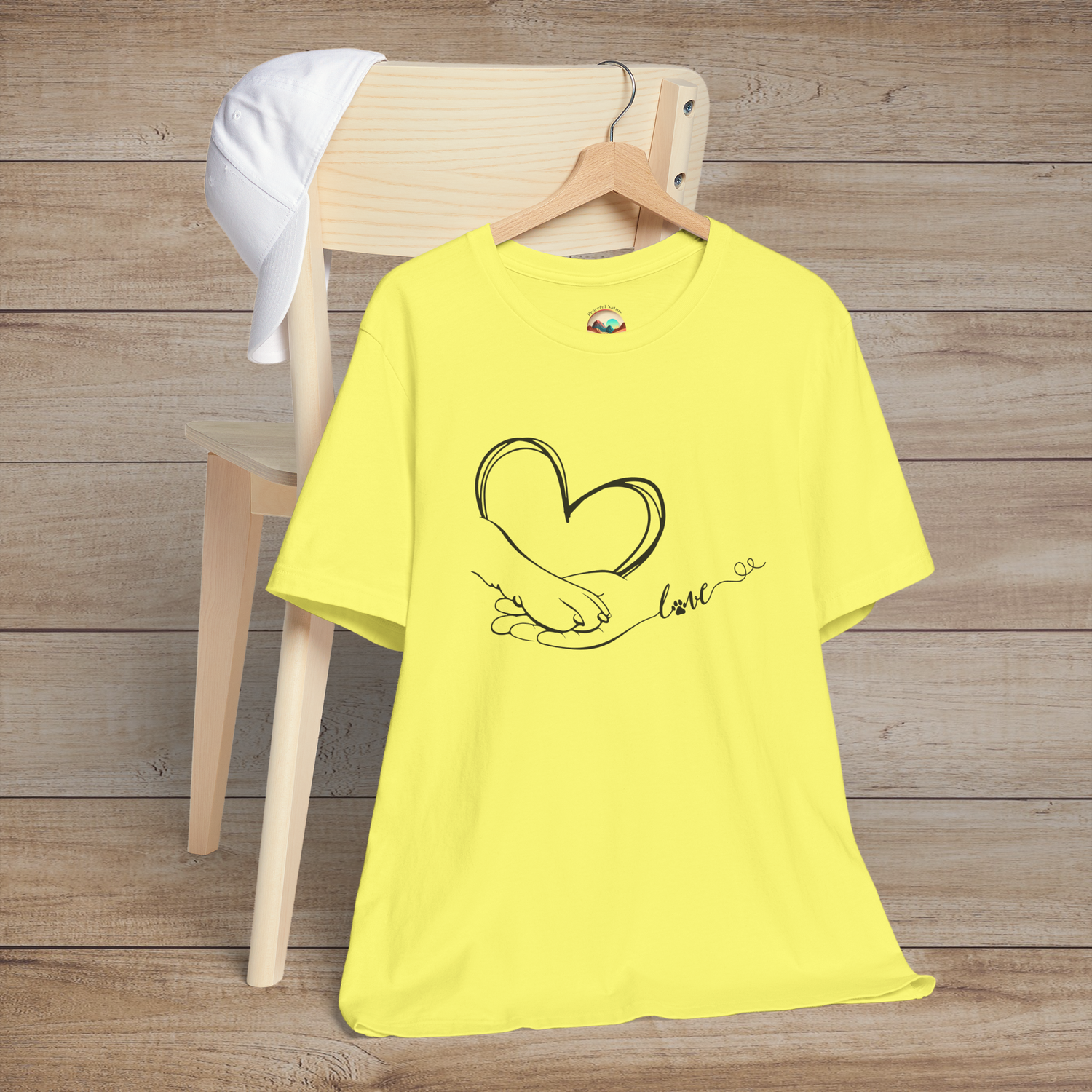 Yellow t-shirt with delicate minimalist design showing a hand and paw forming a heart shape with love written in flowing script