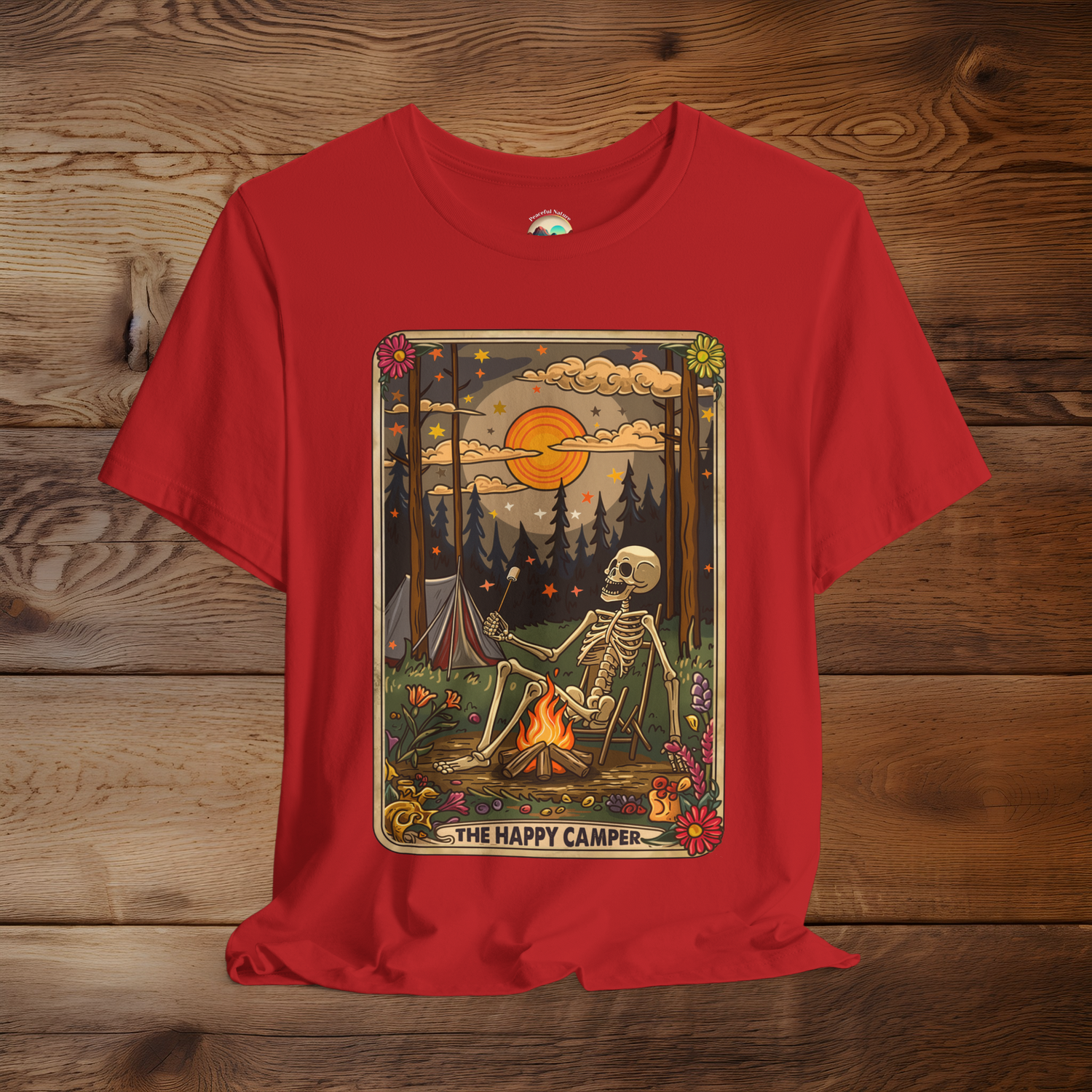 Red Happy Camper Tarot T-Shirt showing a skeleton lounging by a campfire, surrounded by flowers and forest