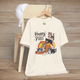 Natural-colored t-shirt featuring Happy Pills design with kittens tumbling from a prescription bottle