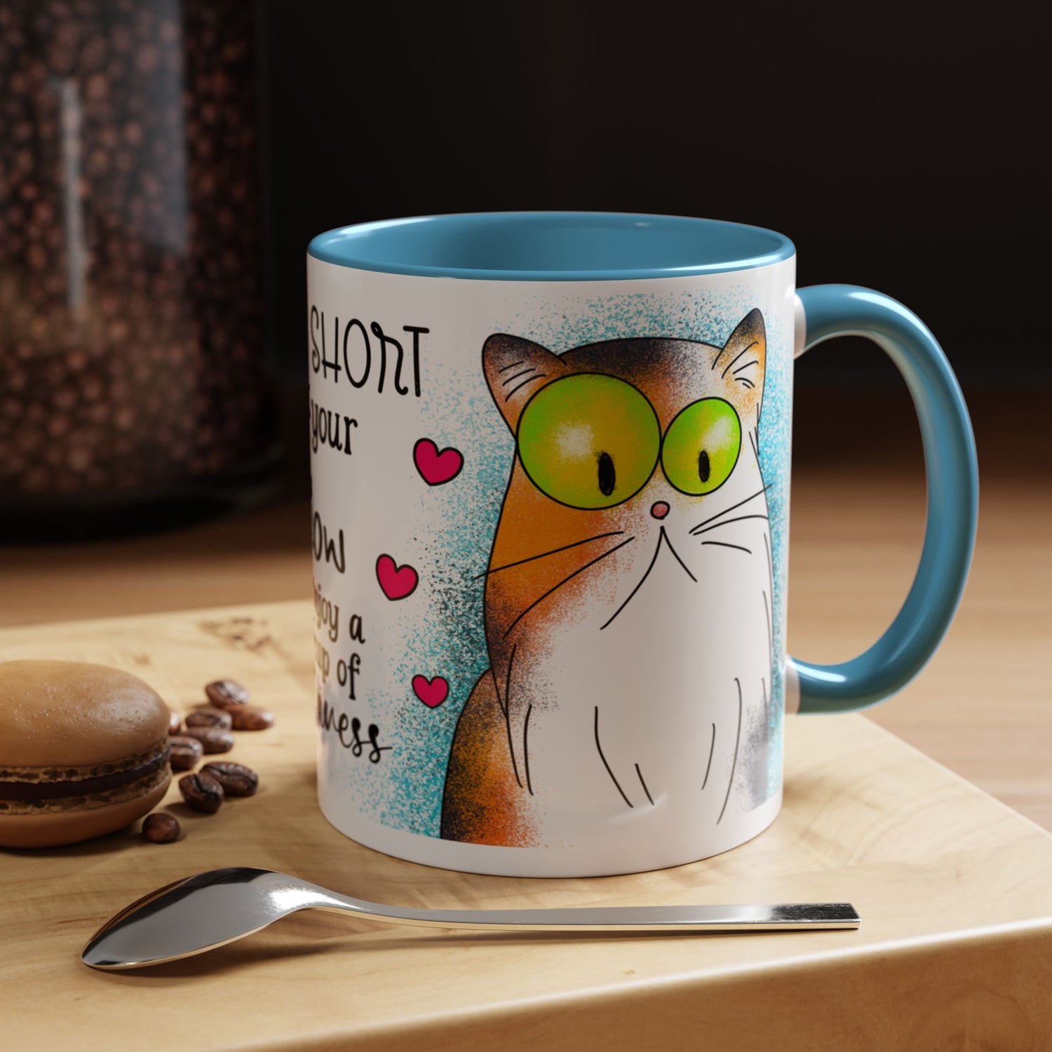 Right-side view of the 11 oz Hug Your Meow Mug with light blue trim, featuring a wide-eyed cartoon cat surrounded by playful red hearts and vibrant blue background accents. A fun and cozy gift for cat lovers.