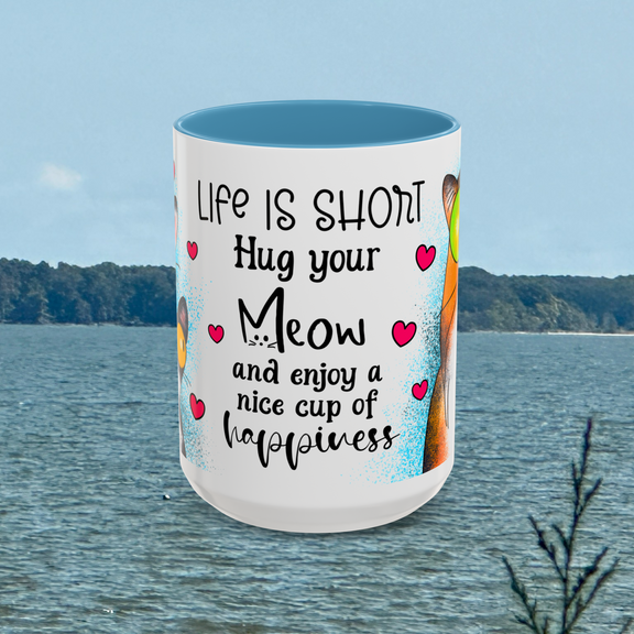Front view of the 15 oz Hug Your Meow Mug featuring the phrase 'Life is short, Hug your Meow and enjoy a nice cup of happiness' in bold black font with pink hearts, accented with light blue trim. Ideal for cat moms and dads