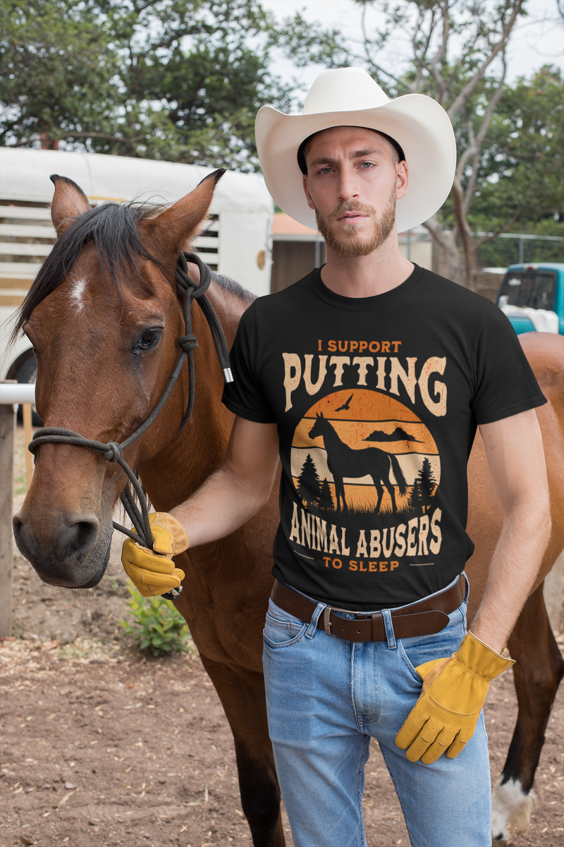 Man wearing a black t-shirt with a graphic and text that states, "I support putting animal abusers to sleep," standing next to a horse.