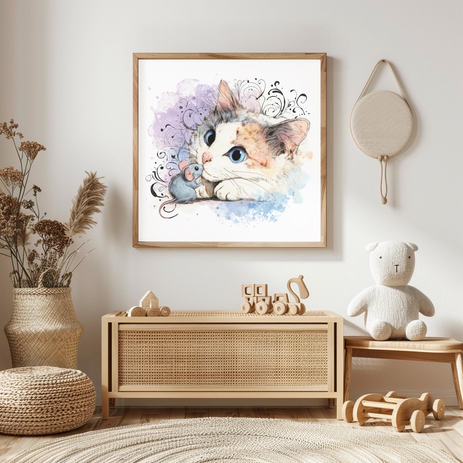 May include: Watercolor print of a cat and mouse. The cat has blue eyes and a calico coat, with a small gray mouse beside it. The artwork is framed in a light wood frame and hangs on a white wall.