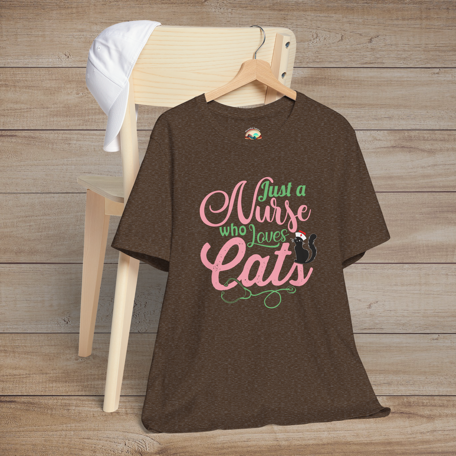 Heather brown t-shirt displaying elegant Just a Nurse Who Loves Cats text in pink and green with a cute black cat sitting on the word Cats