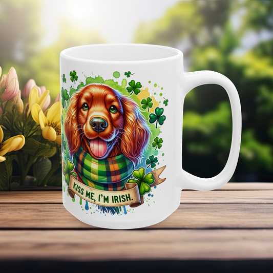 White 15 oz St. Patrick’s Day mug showing a smiling red dog with a green plaid scarf, festive shamrocks, and "Kiss Me, I'm Irish" ribbon, set on a rustic outdoor table with yellow flowers in the background