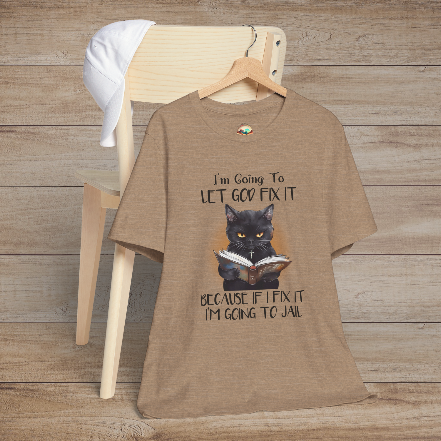 Heather tan Let God Fix It T-Shirt with a serious black cat holding a book and humorous faith-inspired message