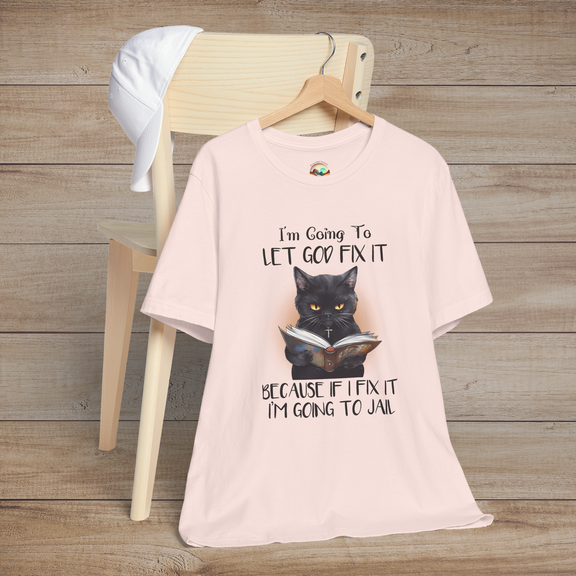 Soft pink Let God Fix It T-Shirt with a black cat wearing a necklace and reading a book with a humorous Christian quote