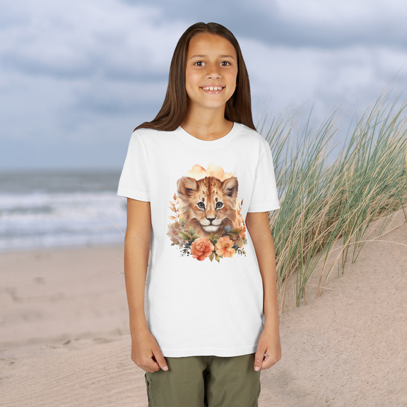 Youth girl wearing a white Lion Cub Floral Youth T-Shirt with a charming lion cub and floral watercolor design, sandy beach setting